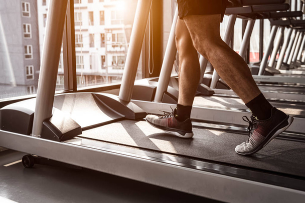 Close up of sport man running on treadmill in fitness gym at con - Valokuva, kuva