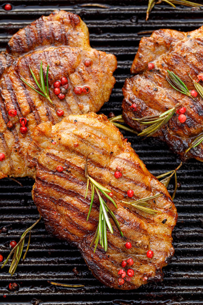 Grilled pork steaks, pork neck with the addition of herbs and spices on the grill plate, top view, Grilled meat, bbq, barbecue grill - Photo, Image