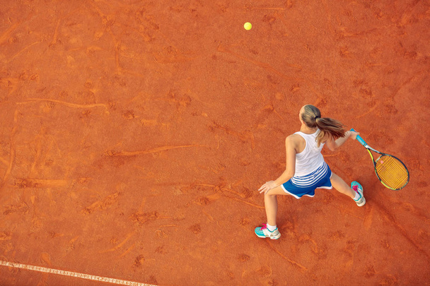 Aerial shot of a female tennis player on a court during match. Young woman playing tennis.High angle view. - Foto, Bild
