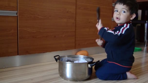 χαριτωμένο δύο χρονών αγόρι προσποιούνται ότι μαγειρεύουν σούπα από τα ρούχα του μωρού και χαρτί - Πλάνα, βίντεο