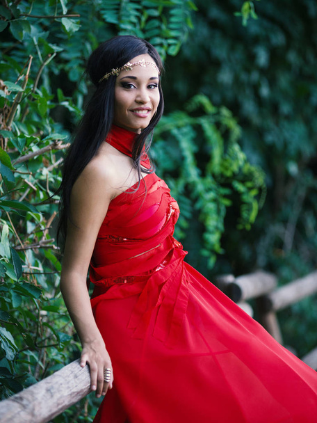 Happy young woman smiling portrait wearing red dress outdoors in a park. - Photo, Image