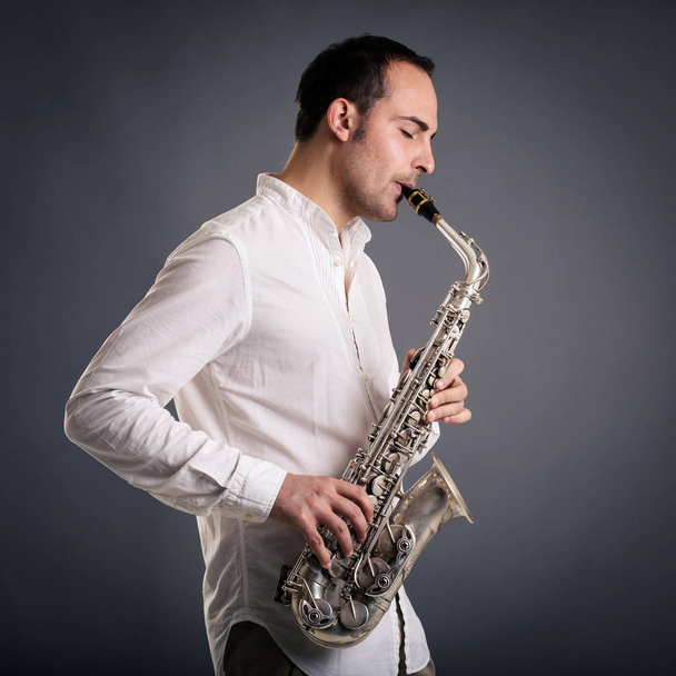 Saxophone player man isolated against dark background. Close up studio portrait. - Φωτογραφία, εικόνα