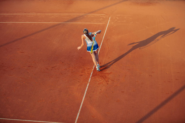 Woman playing tennis on clay court, with sporty outfit and healthy lifestyle - Fotografie, Obrázek