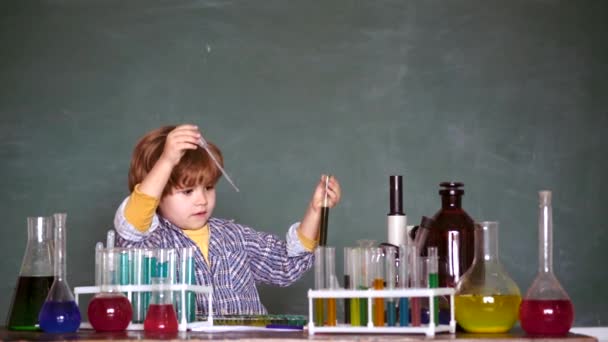 Child in the class room with blackboard on background. Chemistry lesson. Little kids scientist earning chemistry in school lab. Lab microscope and testing tubes. - Záběry, video