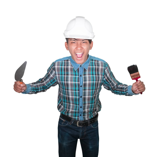 μηχανικός θυμωμένος με το χέρι κρατώντας τρίγωνο σπάτουλα και βαφή βούρτσα φορούν λευκό κράνος ασφαλείας πλαστικό σε λευκό φόντο - Φωτογραφία, εικόνα