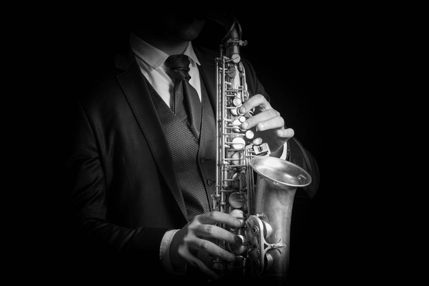 Detail of Saxophone and man hands isolated against black background. Close up studio portrait, black and white image. - Фото, зображення