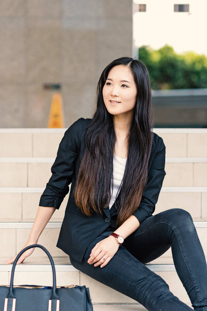 Young businesswoman portrait sit on stairs outdoors. - 写真・画像