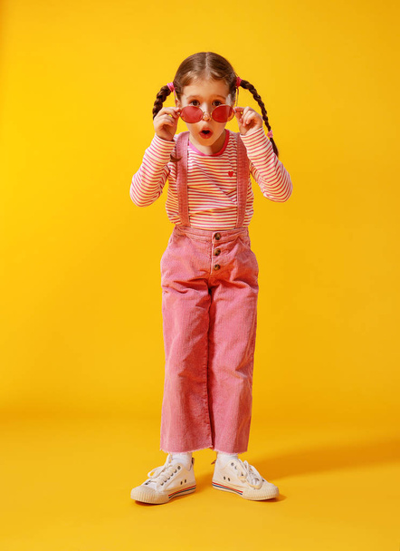 divertente divertente bambino ragazza in abiti rosa su sfondo giallo
    - Foto, immagini