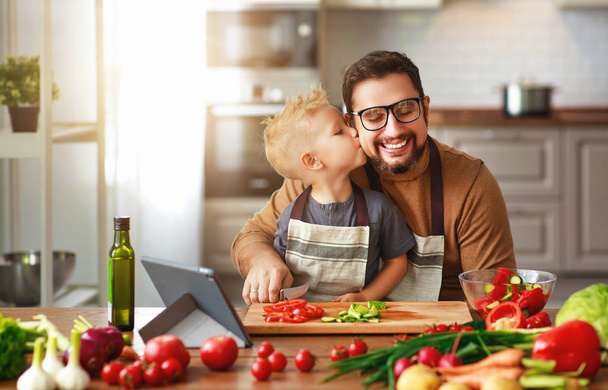 счастливый отец семьи с сыном, готовящим овощной салат
 - Фото, изображение