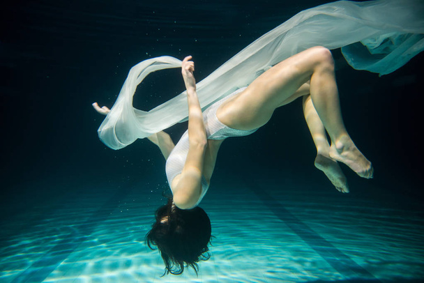 Underwater woman upside down portrait in swimming pool at night. - Photo, Image