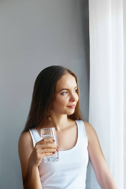 Healthy lifestyle.Young woman drinking from a glass of fresh water. Healthcare. Drinks. Portrait of happy smiling female model holding transparent glass. Health,Beauty,Diet concept. Healthy eating - Fotografie, Obrázek