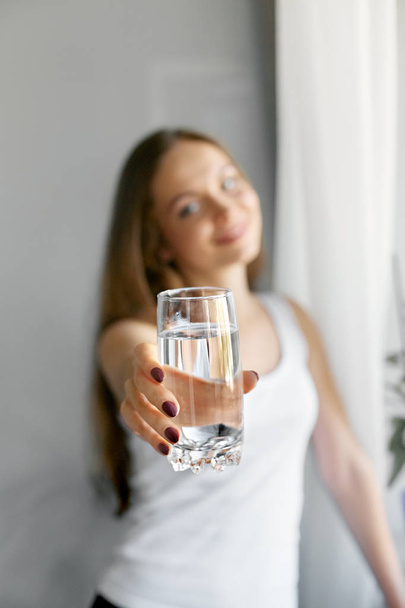 Closeup young woman show glass of water. Portrait of happy smiling female model holding transparent glass of water.Healthy lifestyle. Beauty, Diet concept  - Foto, afbeelding