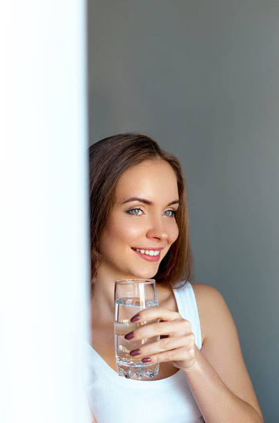 Healthy lifestyle.Young woman drinking from a glass of fresh water. Healthcare. Drinks. Portrait of happy smiling female model holding transparent glass. Health,Beauty,Diet concept. Healthy eating - Foto, immagini
