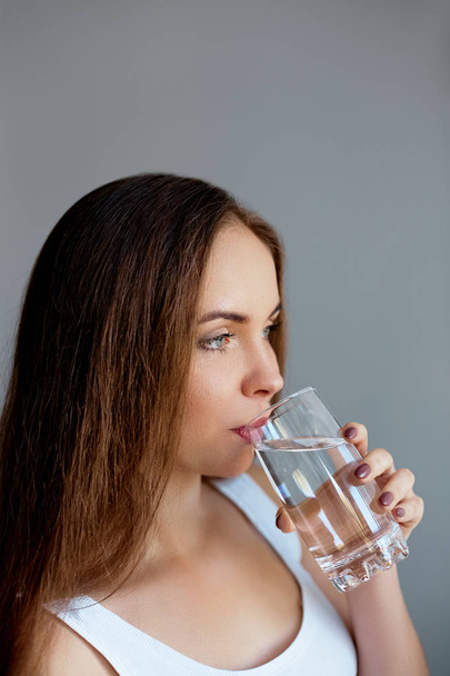 Healthy lifestyle.Young woman drinking from a glass of fresh water. Healthcare. Drinks. Portrait of happy smiling female model holding transparent glass. Health,Beauty,Diet concept. Healthy eating - Zdjęcie, obraz