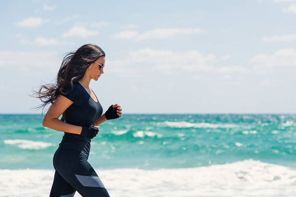Young beautiful brunette woman running outdoors on the beach. Miami, Florida. - Photo, Image