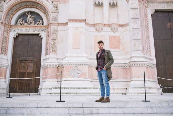 Young man portrait standing in front of San Petronio Cathedral in the city center of Bologna, Italy. - Фото, изображение