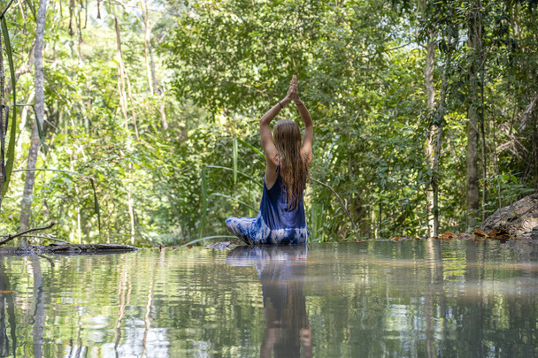 Beautiful woman practicing yoga near turquoise water of cascade waterfall at deep tropical rain forest, island Koh Phangan, Thailand - Фото, зображення
