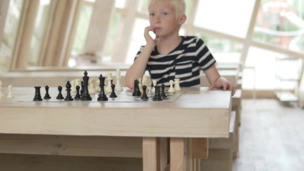 Przystojny blond chłopiec gra w szachy. - Materiał filmowy, wideo