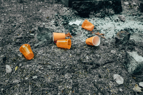 Oranje wegwerp plastic glas of bekers gebruikt voor drinkwater in een bin-milieuprobleem concept. Niet-compobaar afval - Foto, afbeelding