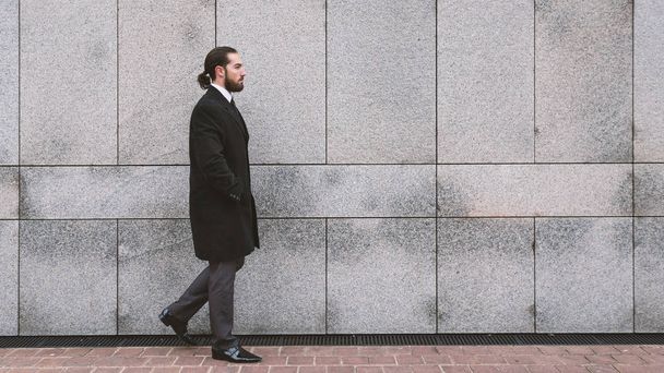 Full body portrait of young businessman walking against wall. Defense District. Paris, France.  - 写真・画像