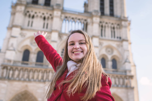 Feliz joven rubia señalando la Catedral de Notre Dame en la ba
 - Foto, imagen