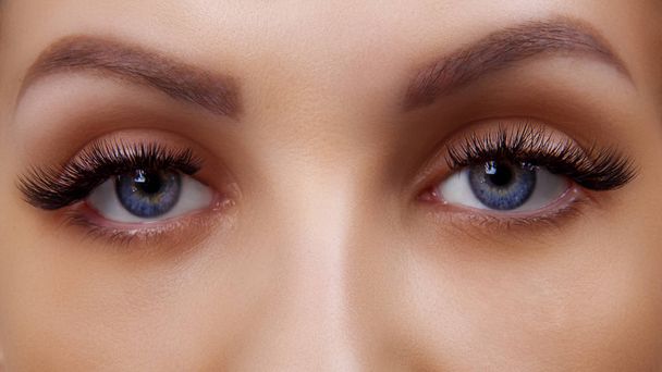Eyelash Extension Procedure. Woman Eye with Long Blue Eyelashes. Ombre effect. Close up, selective focus. - Foto, Imagen