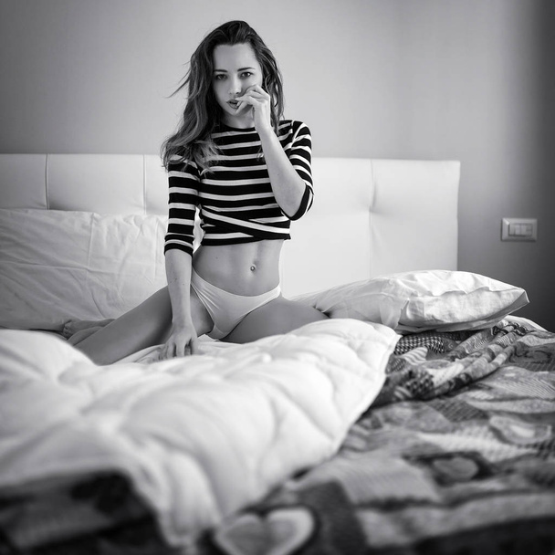 Sensual young woman close up portrait at home laying on her bed. Black and white image. - Foto, Imagen