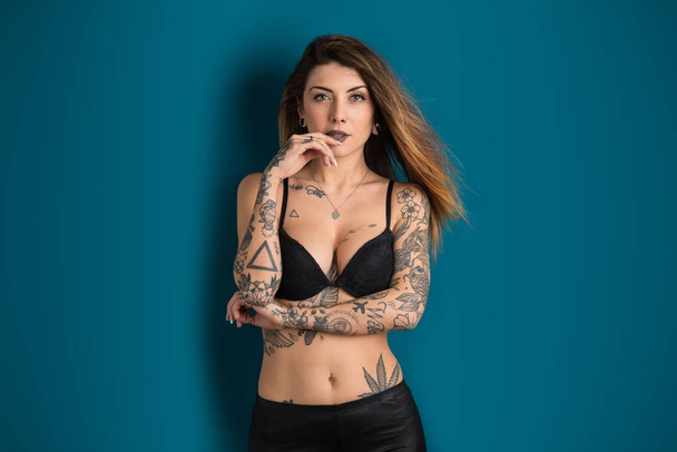 Beautiful woman studio portrait with tattoo against blue backgro - Photo, image