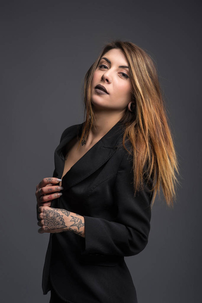 Confident woman portrait with long black jacket and tattoos. - Фото, изображение