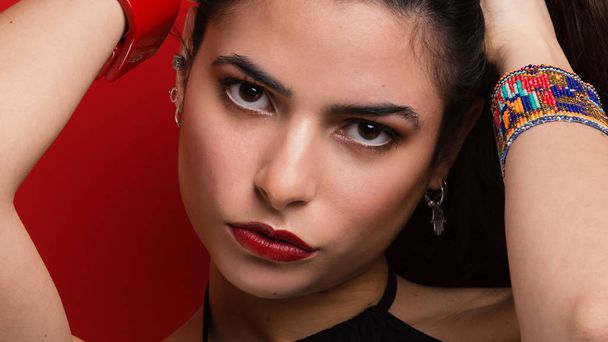 Beautiful young woman close up portrait against red background. - 写真・画像