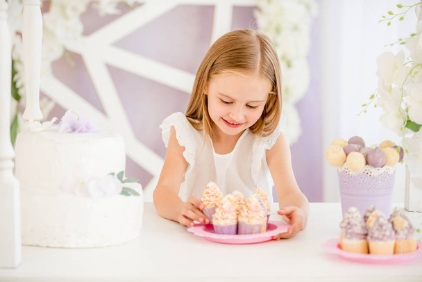 Little girl holding a pink plate with sweet cakes in the candy bar - Photo, image