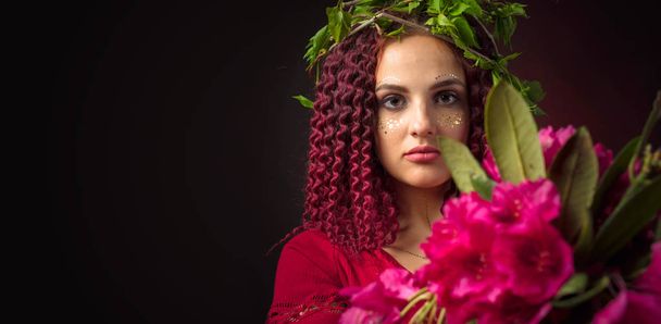の花束を持つ赤いドレスを着た魅力的な若い女性の肖像画  - 写真・画像