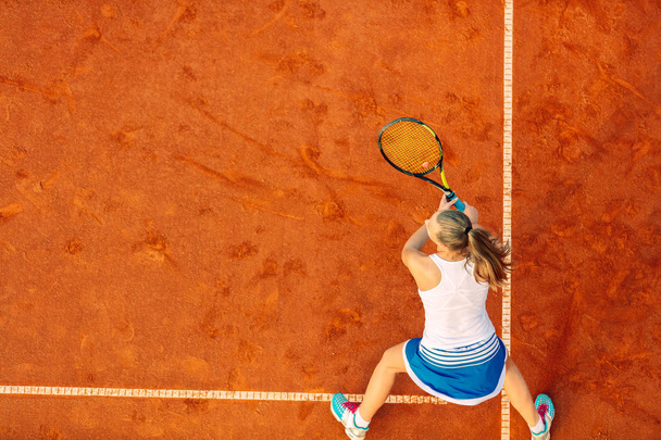 Aerial shot of a female tennis player on a court during match. Young woman playing tennis.High angle view. - Zdjęcie, obraz