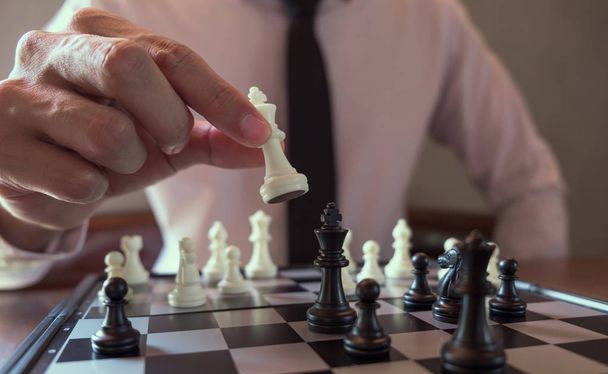 Closeup photo of businessman playing chess and beating black kin - Foto, imagen
