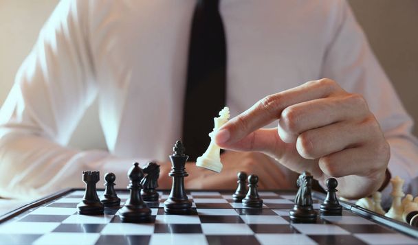 Closeup photo of businessman playing chess and beating black kin - Foto, afbeelding