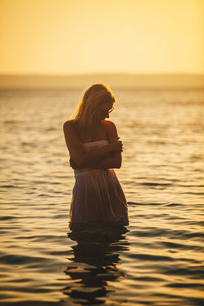 Beautiful young pregnant woman playing with water at the sea in the summer at sunset Concept Love and pregnancy - Fotografie, Obrázek