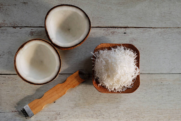 Geraspte kokos en half gesneden kokos op houten vloer, TopView - Foto, afbeelding