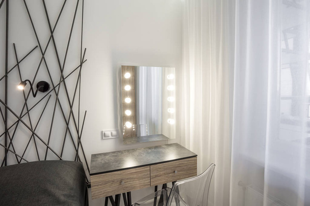 MINSK, BELARUS - January, 2019: bedside table with mirror and led lamps in Interior of the modern bedroom in loft flat in light color style of expensive apartments - Fotó, kép