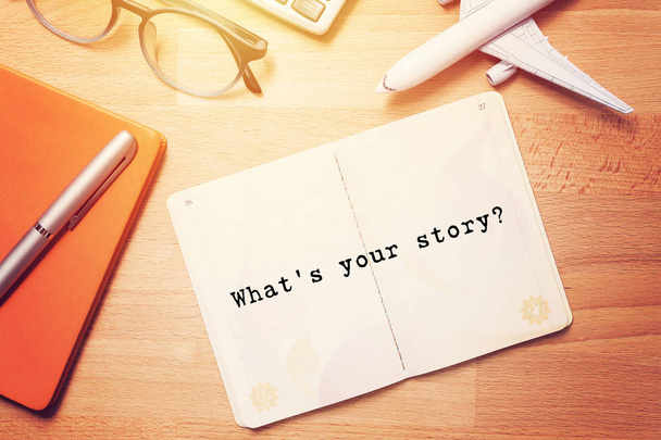 what's your story? notebook with text at blank page on wooden background with glasses and plane model - Fotó, kép