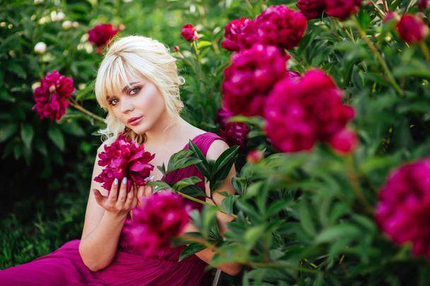 Outdoor close up portrait of beautiful young woman in the blooming garden. Female spring fashion concept - Фото, изображение
