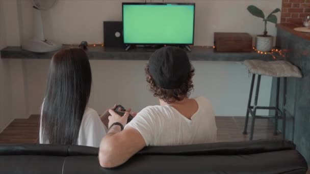 man and woman sitting on couch playing video games on green screen - Materiał filmowy, wideo