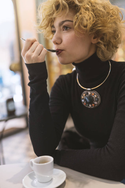Young blonde woman portrait drinking coffee inside a cafe. Shallow depth of field. Life style. - Фото, зображення
