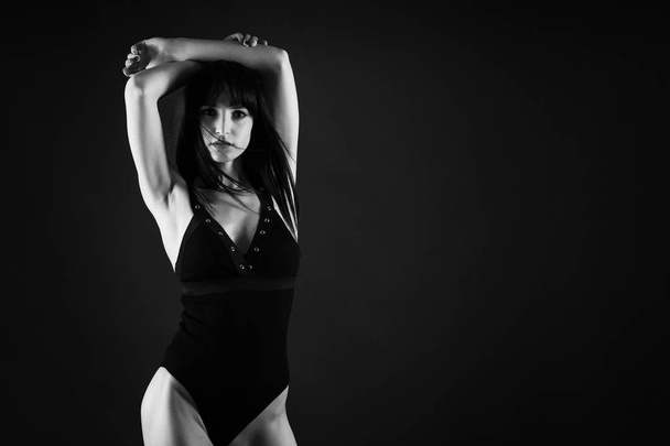 Sexy confident woman portrait wearing black lingerie isolated against dark background. Black and white studio image with film grain effect. - Photo, image