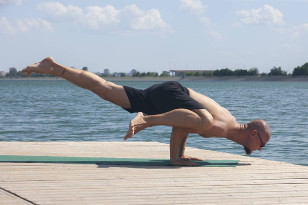 Man doet yoga op een houten vloer in de natuur - Foto, afbeelding