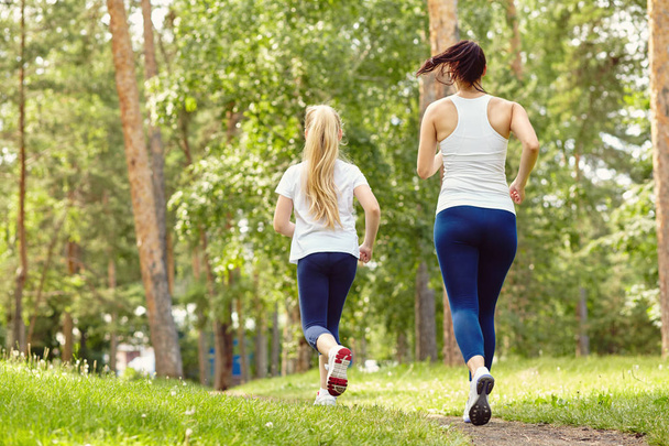 running sporty mother and daughter. woman and child jogging in park. outdoor sports and fitness family - Fotoğraf, Görsel