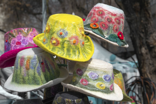 Multicolored handmade women's hats made of felt with decorations and embroidery are sold in the shop on the street - Photo, Image