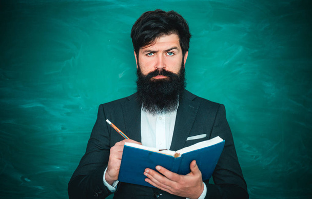 Teachers day - knowledge and educational school concept. Young bearded teacher near chalkboard in school classroom. Tutoring. - Fotografie, Obrázek