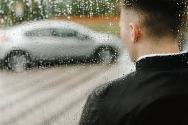 Silhouette de voiture et d'homme à travers le verre recouvert de gouttes de pluie
 - Photo, image