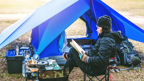 Hombre asiático viaje relajarse acampar en las vacaciones. acampar en la montaña. sentarse relajarse leer un libro En la silla. Tailandia
 - Foto, Imagen