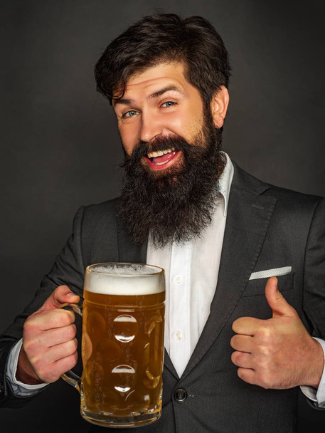Emotional funny bearded drunk hipster holds craft bottled beer. Beard man drinking beer from a beer mug. - Fotó, kép